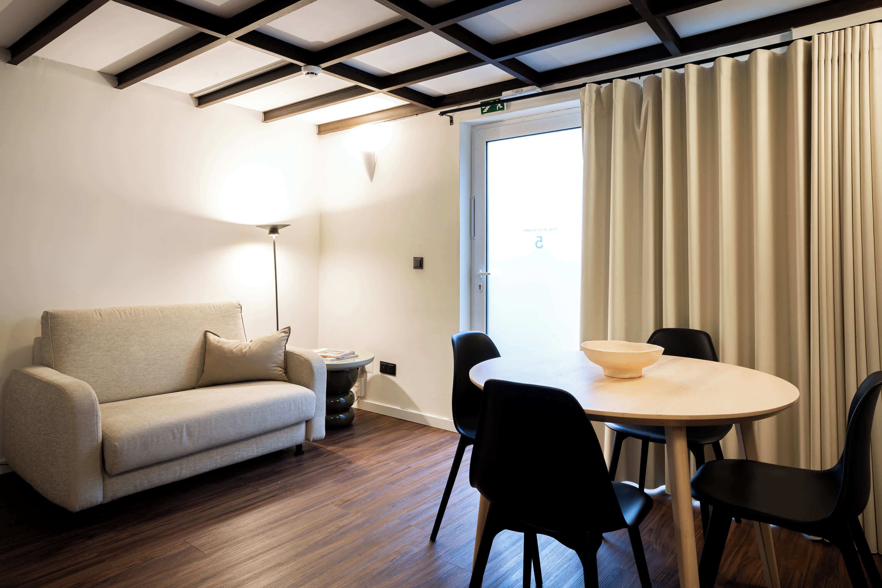 Een moderne woonkamer met een bank, een ronde tafel en zwarte stoelen.