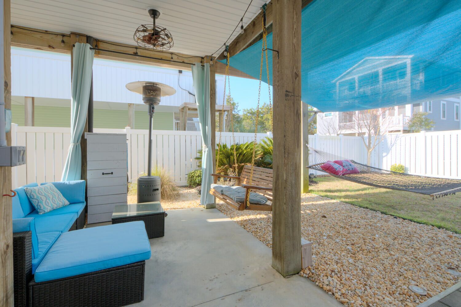 A covered patio area with outdoor furniture, a grill, and a hammock.