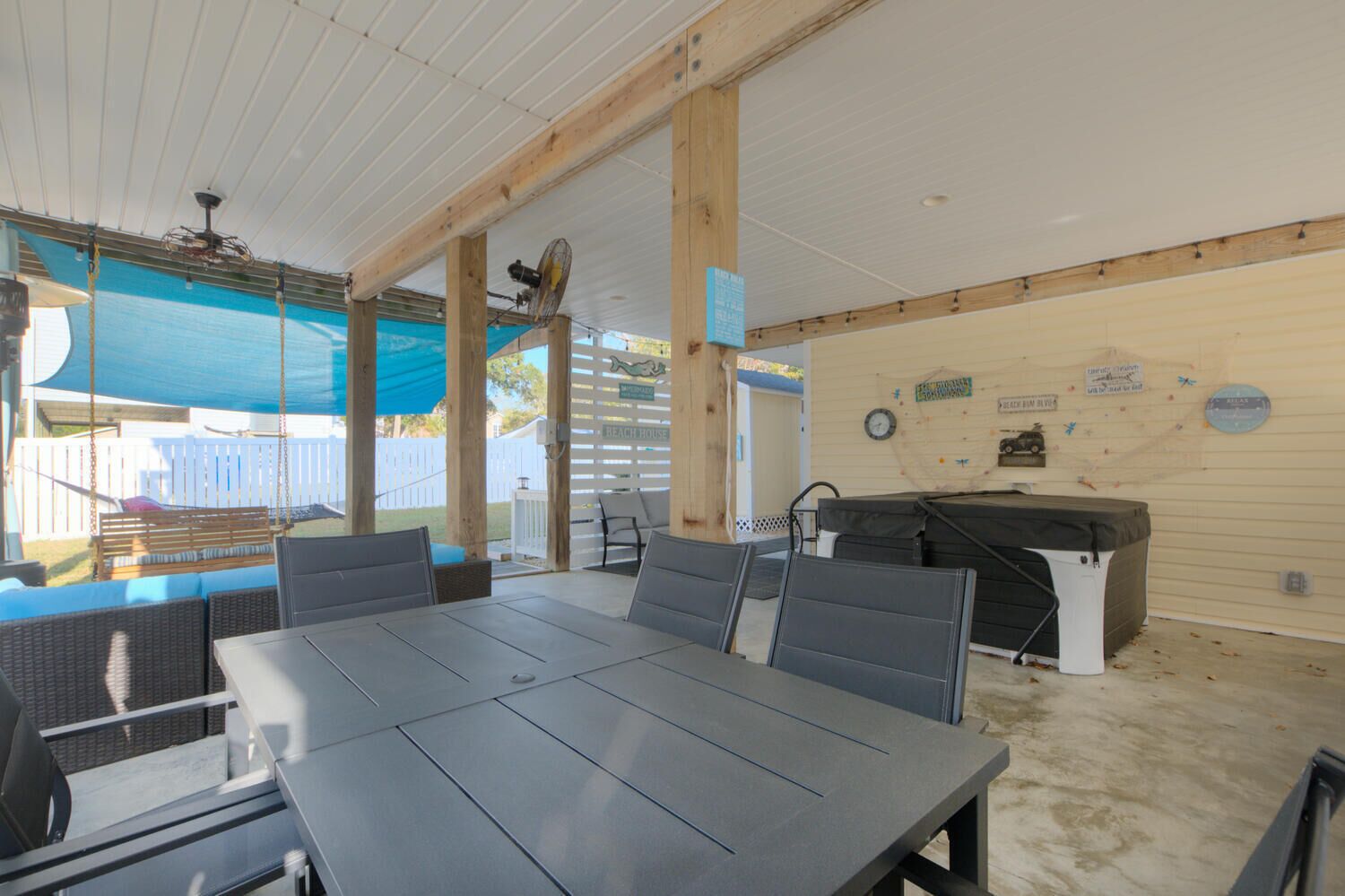 A covered patio with a table and chairs, a grill, and a swing set.