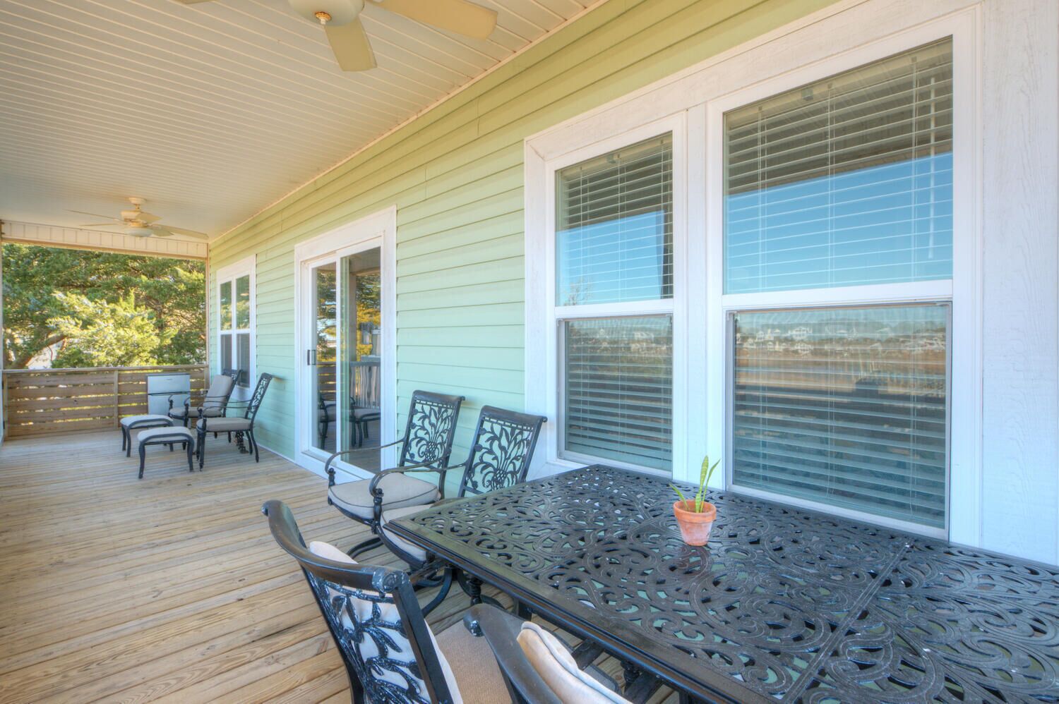 A covered patio with a table and chairs, a ceiling fan, and a view of the outdoors.