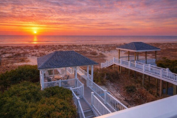 A beach view with two gazebos connected by a wooden walkway. - Experience beachfront luxury at the Resolute, a spacious 4-bedroom escape in Oak Island. (Oak Island)