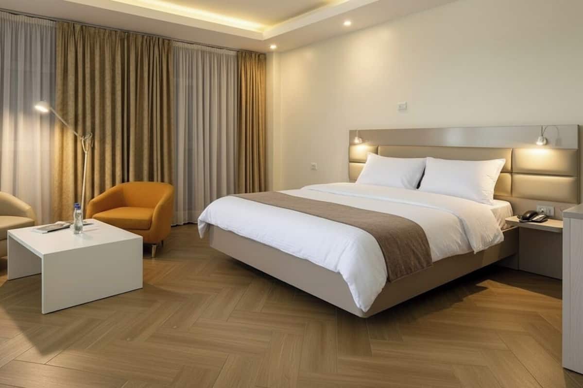 A hotel room with a large bed, two chairs, a bedside table, and a desk.