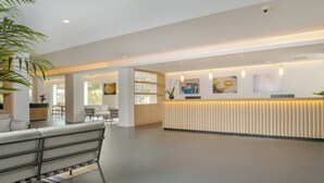 A modern reception area with a reception desk, seating area, and large windows allowing natural light. - Hotel with swimming pool in Olbia (Olbia)