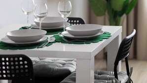 A dining table set with white plates, green placemats, and wine glasses. - Modern Studio for Two | Parking and Air Conditioning (Warszawa)