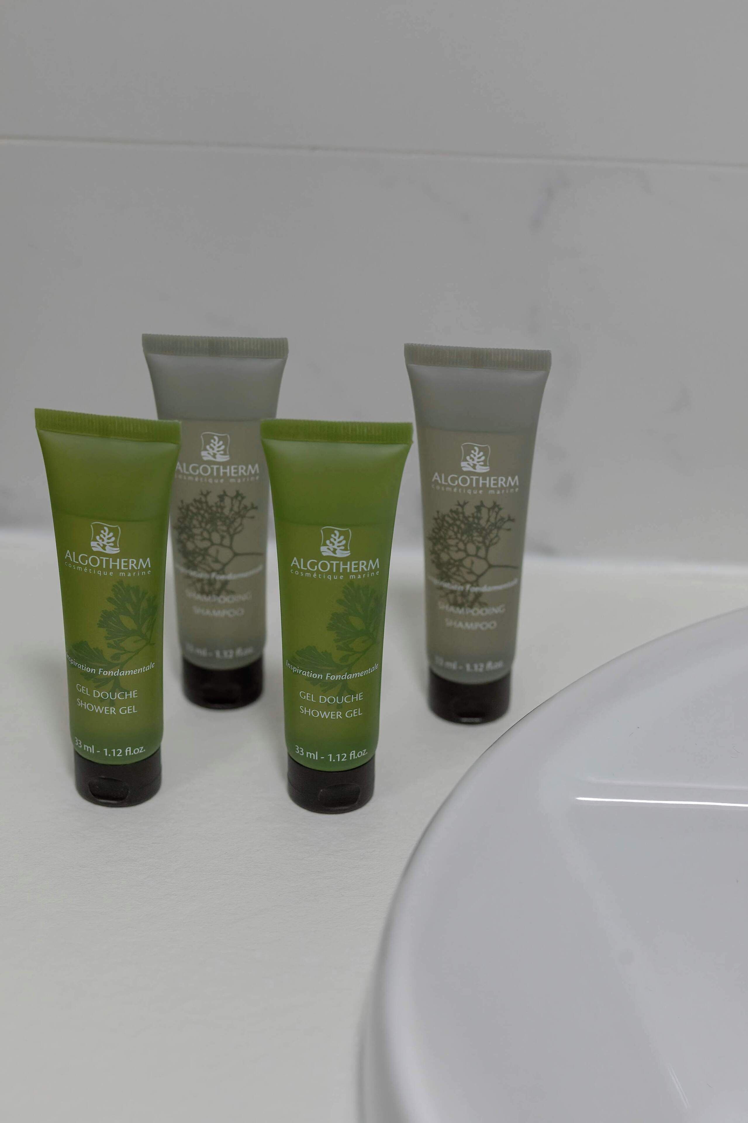 Four bottles of ALGOTHERM shampoo and shower gel on a white surface.