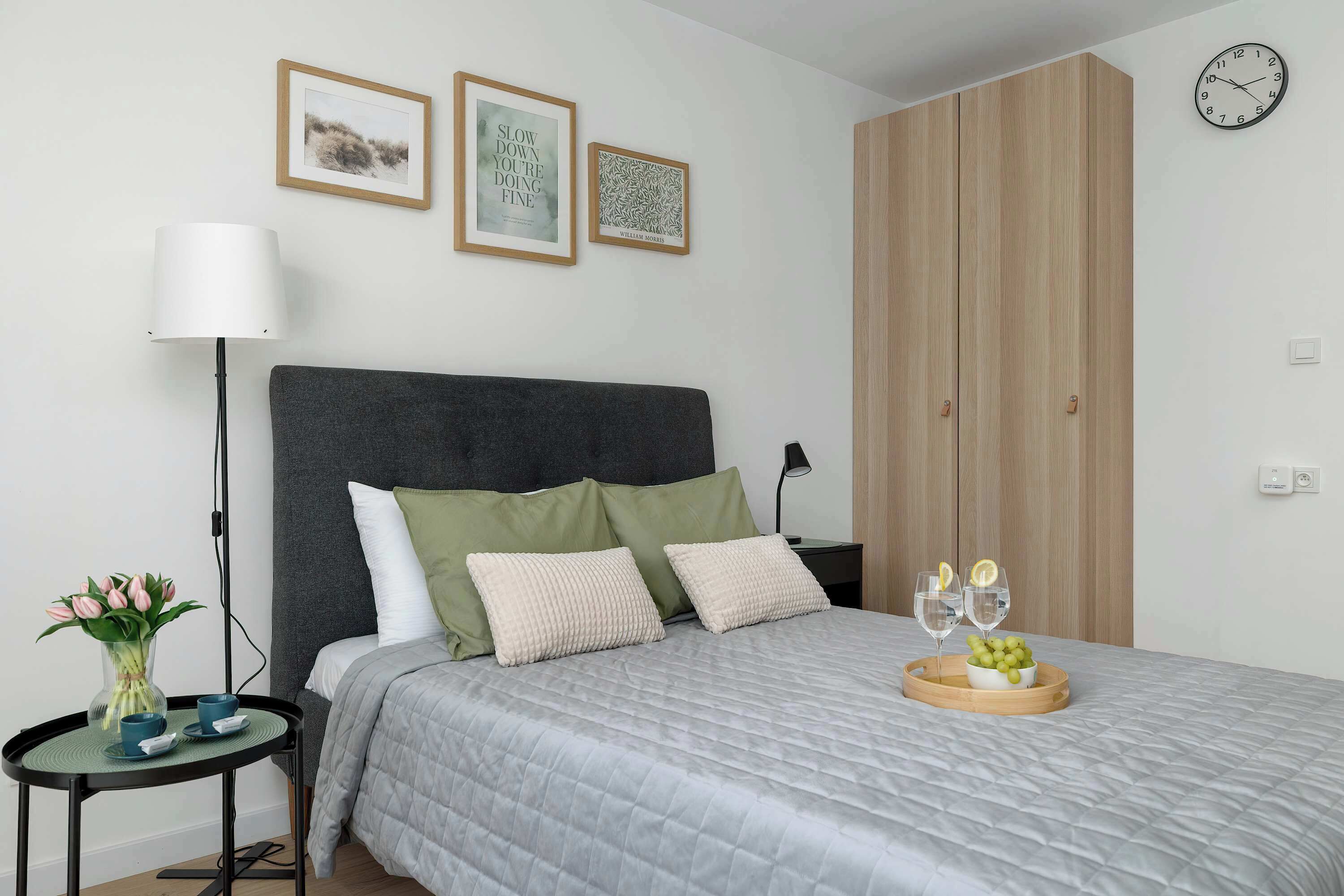 Ein ordentlich eingerichtetes Schlafzimmer mit Bett, Nachttisch, Lampe und Wandbild.