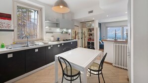 A modern kitchen with a large island, a dining area with chairs, and a view through the window. - Dreamy Lakeview Mornings Await! (Orea)