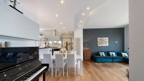 A modern living room with a piano, white dining table, and teal sofa. - Dreamy Lakeview Mornings Await! (Orea)