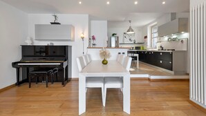 A modern kitchen with a dining area, featuring a piano, white dining table, and contemporary decor. - Dreamy Lakeview Mornings Await! (Orea)