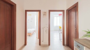 A hallway with wooden doors leading to a bedroom and a bathroom. - Nosdom Properties - National Street (Roma)