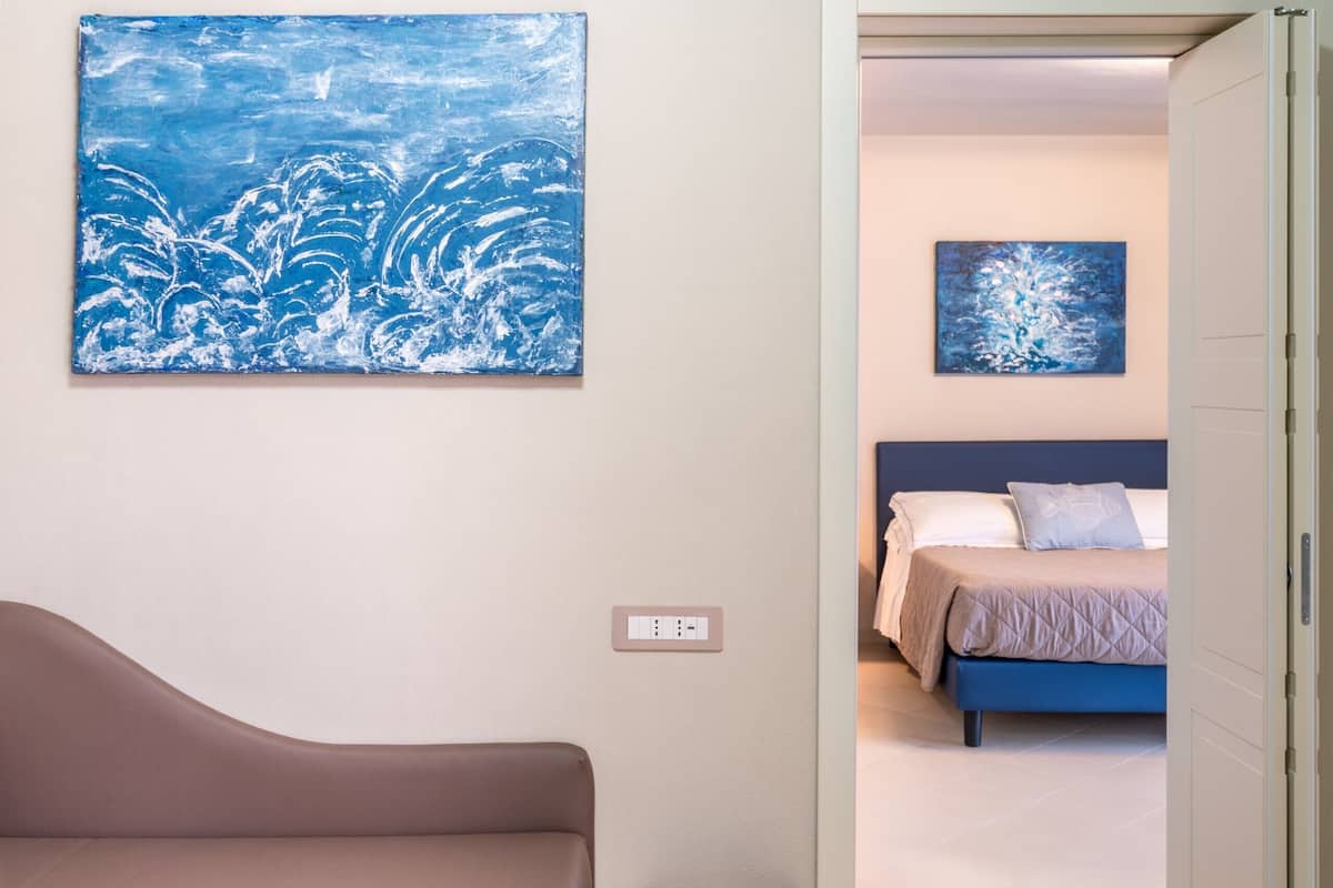Een slaapkamer met een bed, een nachtkastje en een schilderij aan de muur.
