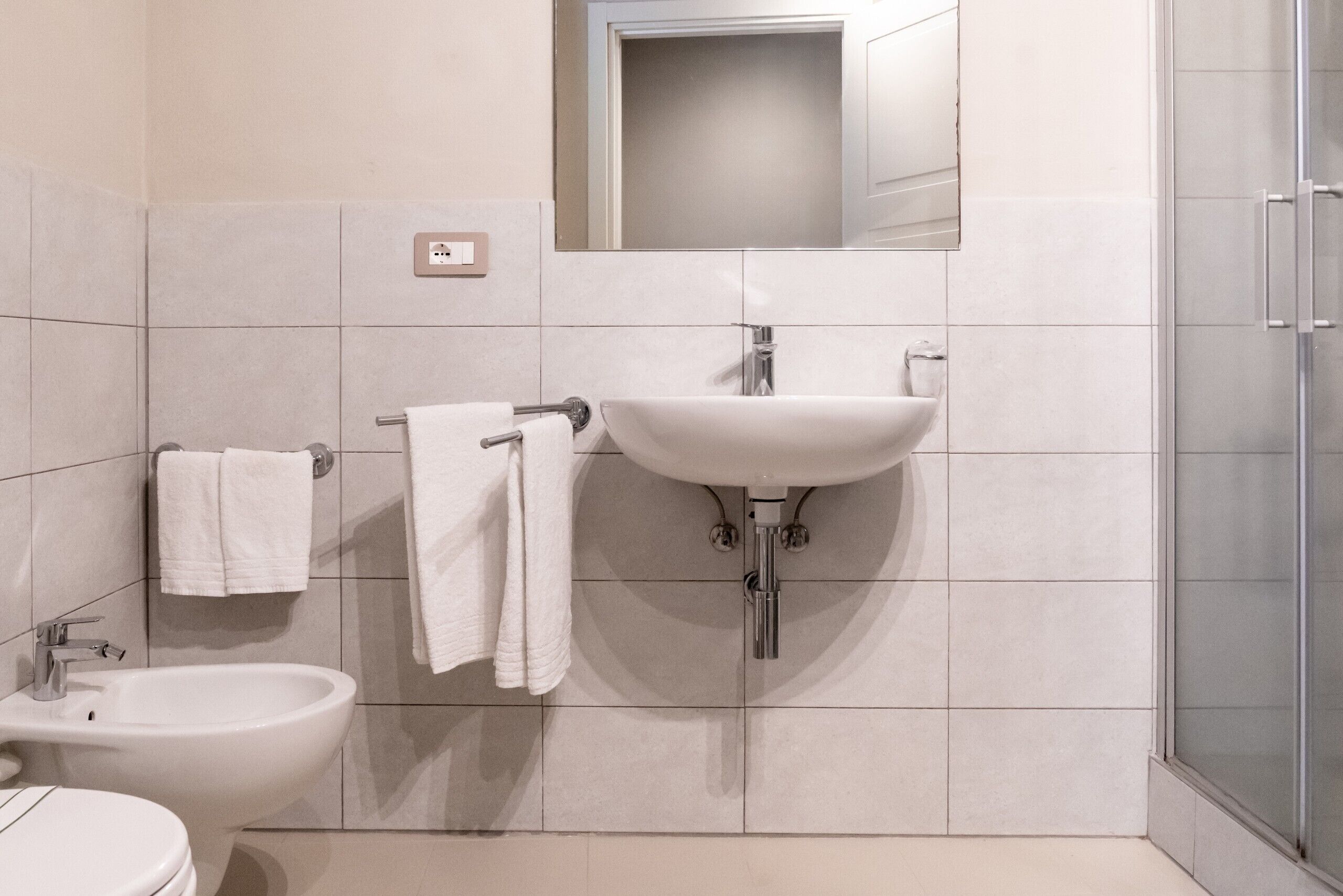 A modern bathroom with a bidet, sink, and toilet.