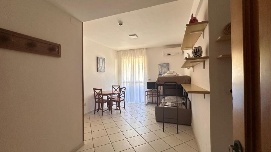 A compact living space with a dining area, a bed, and a small kitchenette.