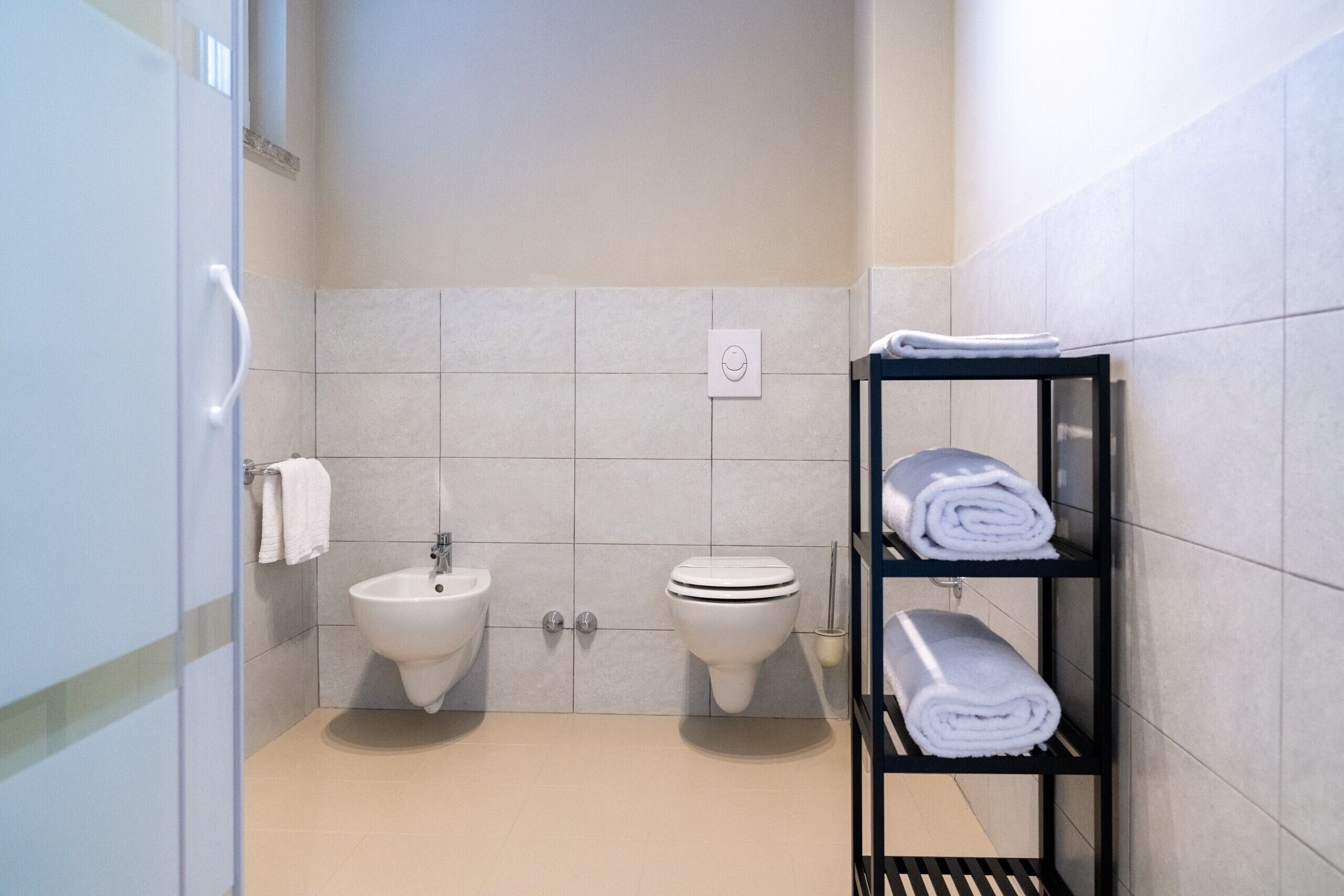 Un baño moderno con dos lavamanos, un inodoro y un perchero para toallas.