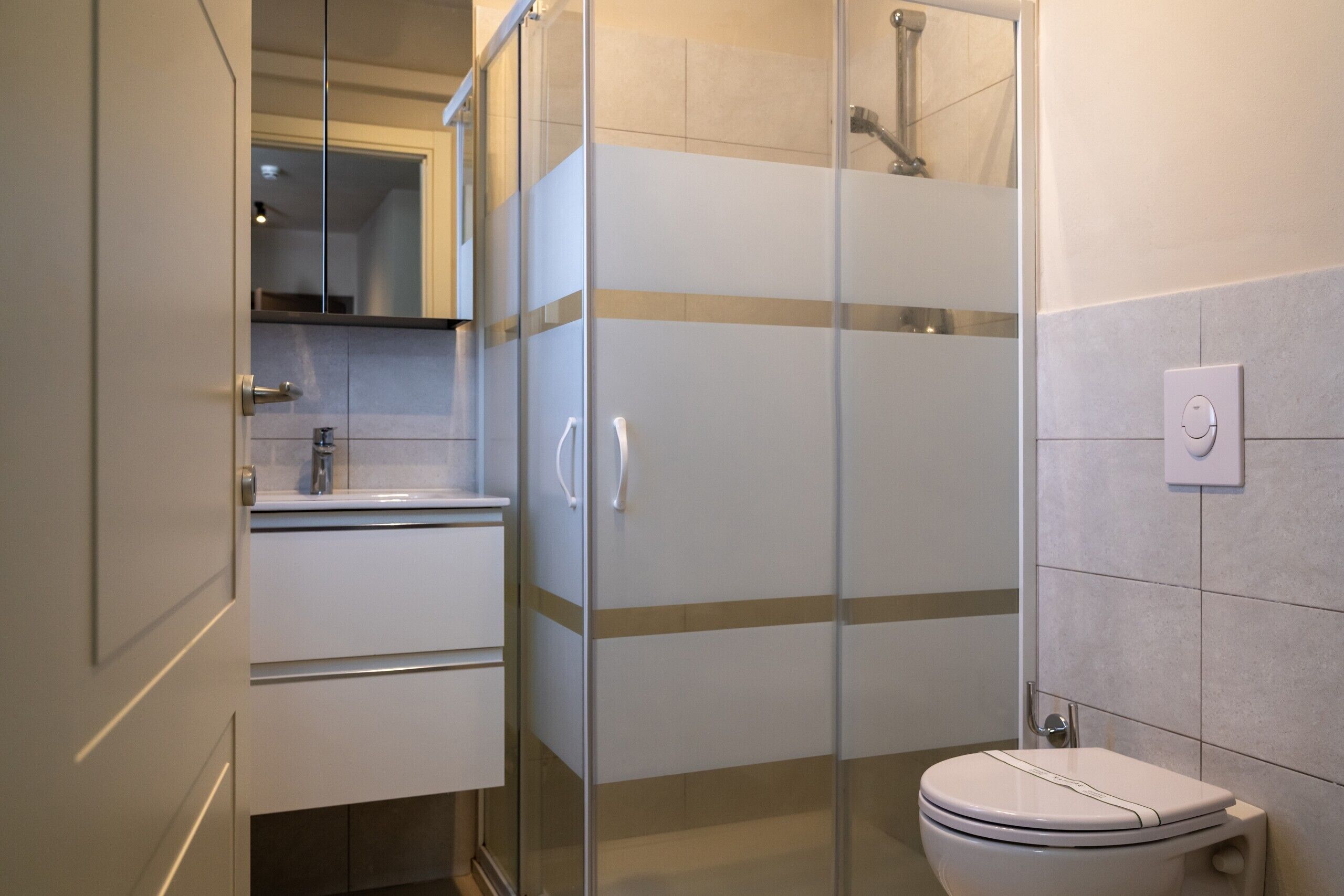 Une salle de bain moderne avec une douche à parois de verre, des toilettes et un lavabo avec un miroir au-dessus.