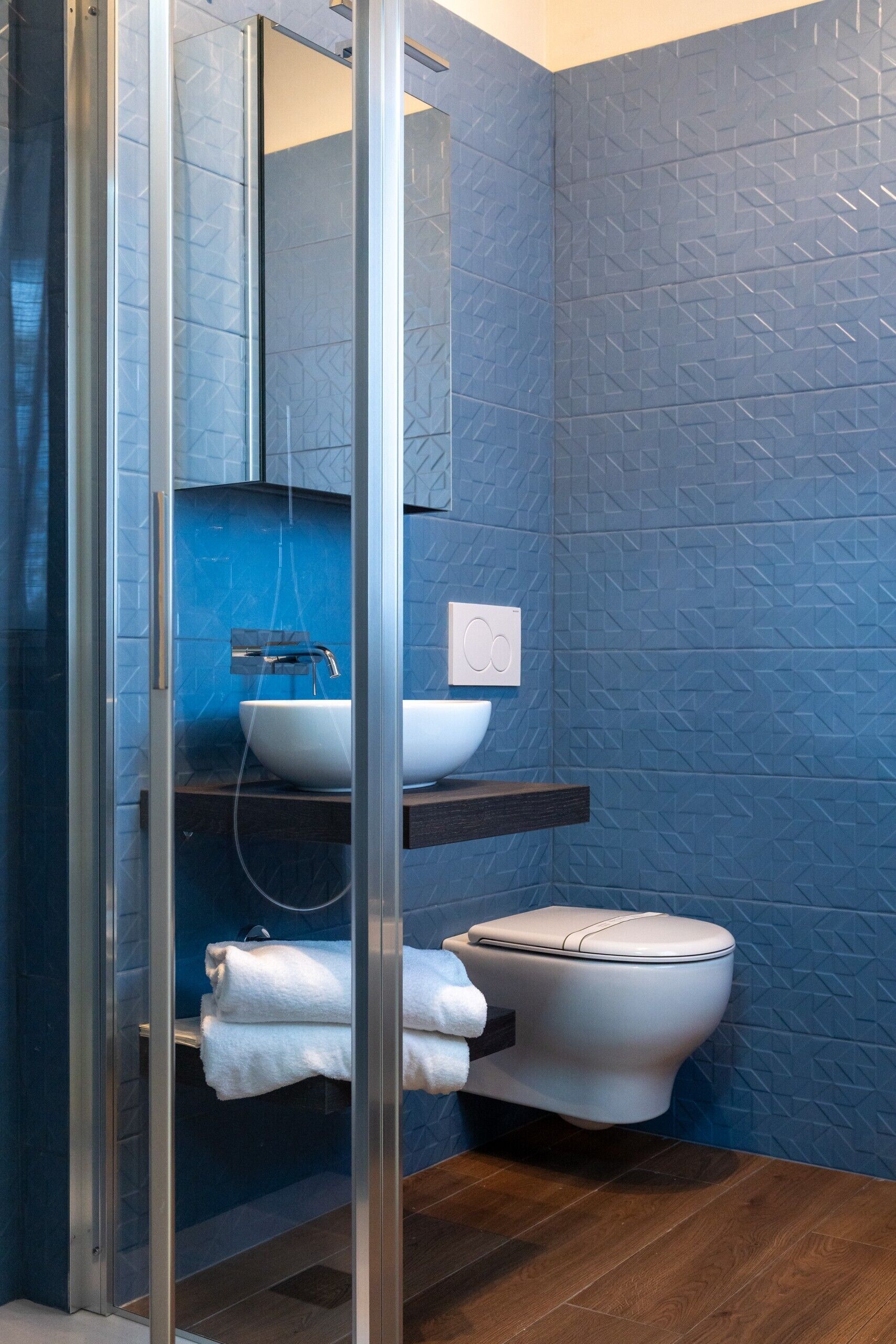 Een moderne badkamer met een douchecabine van glas, een witte wastafel en een toilet.