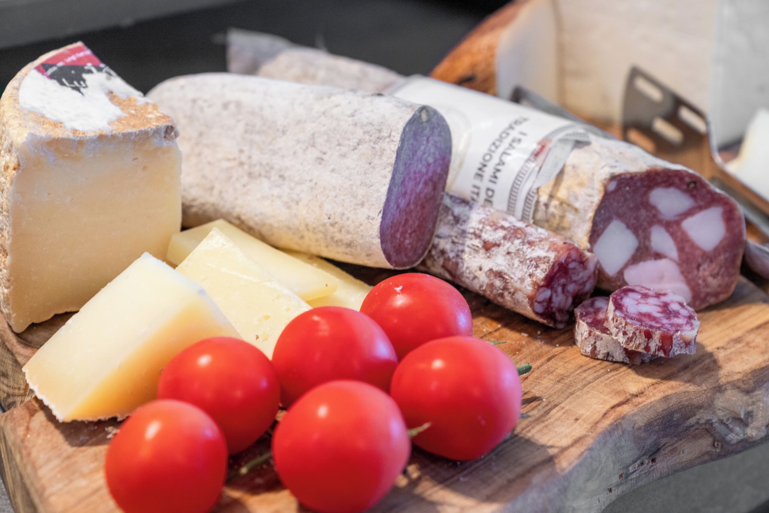 Verschiedene Käsesorten und Tomaten auf einem Holzschneidebrett.