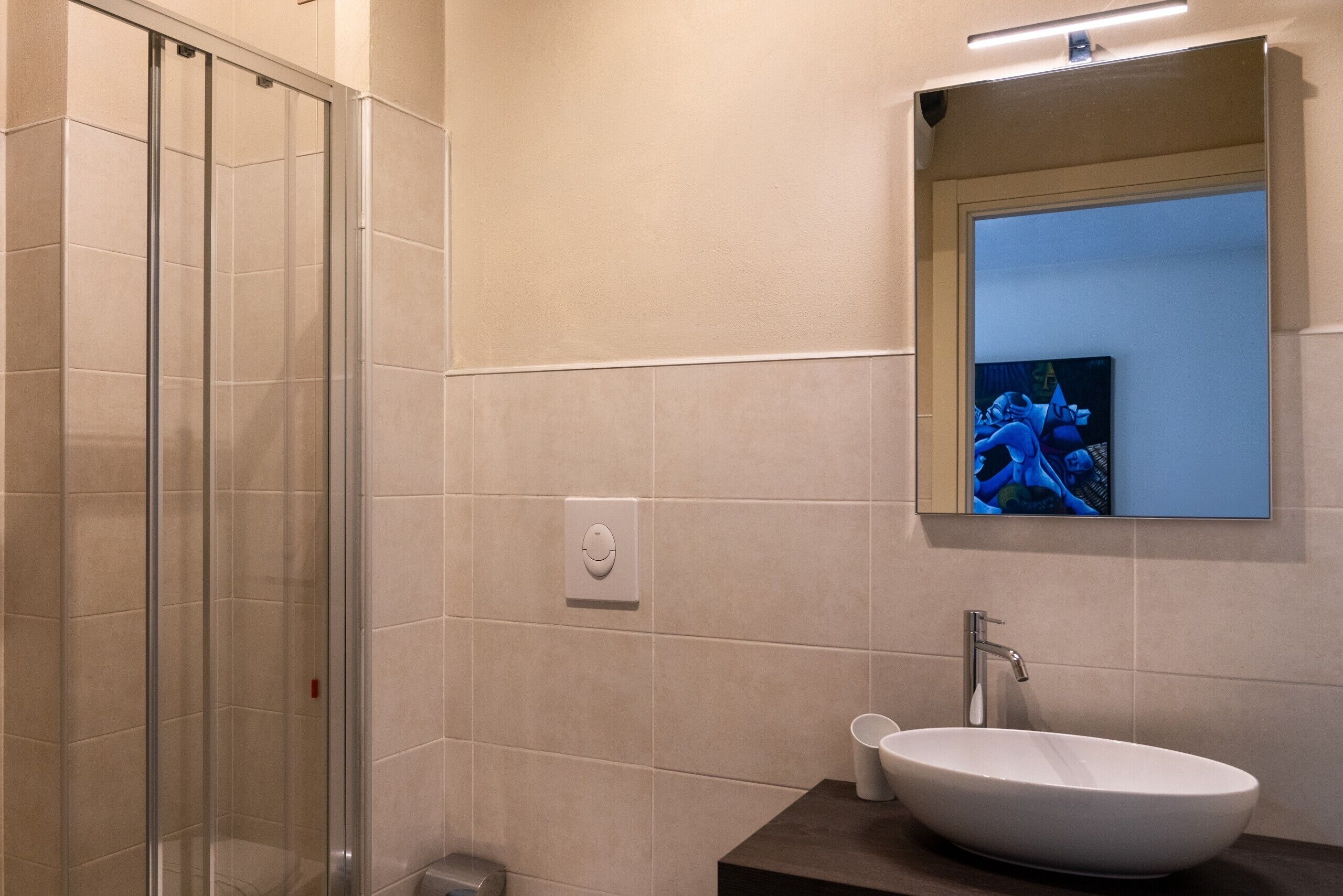 Une salle de bain moderne avec une douche à l’italienne en verre, un lavabo blanc et un miroir au-dessus.