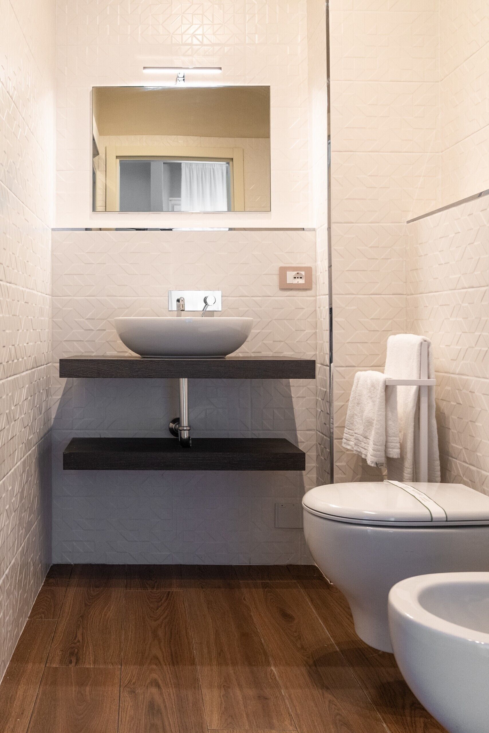 A compact bathroom with a vessel sink, a toilet, and a towel rack.
