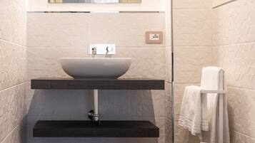 A compact bathroom with a vessel sink, a toilet, and a towel rack.