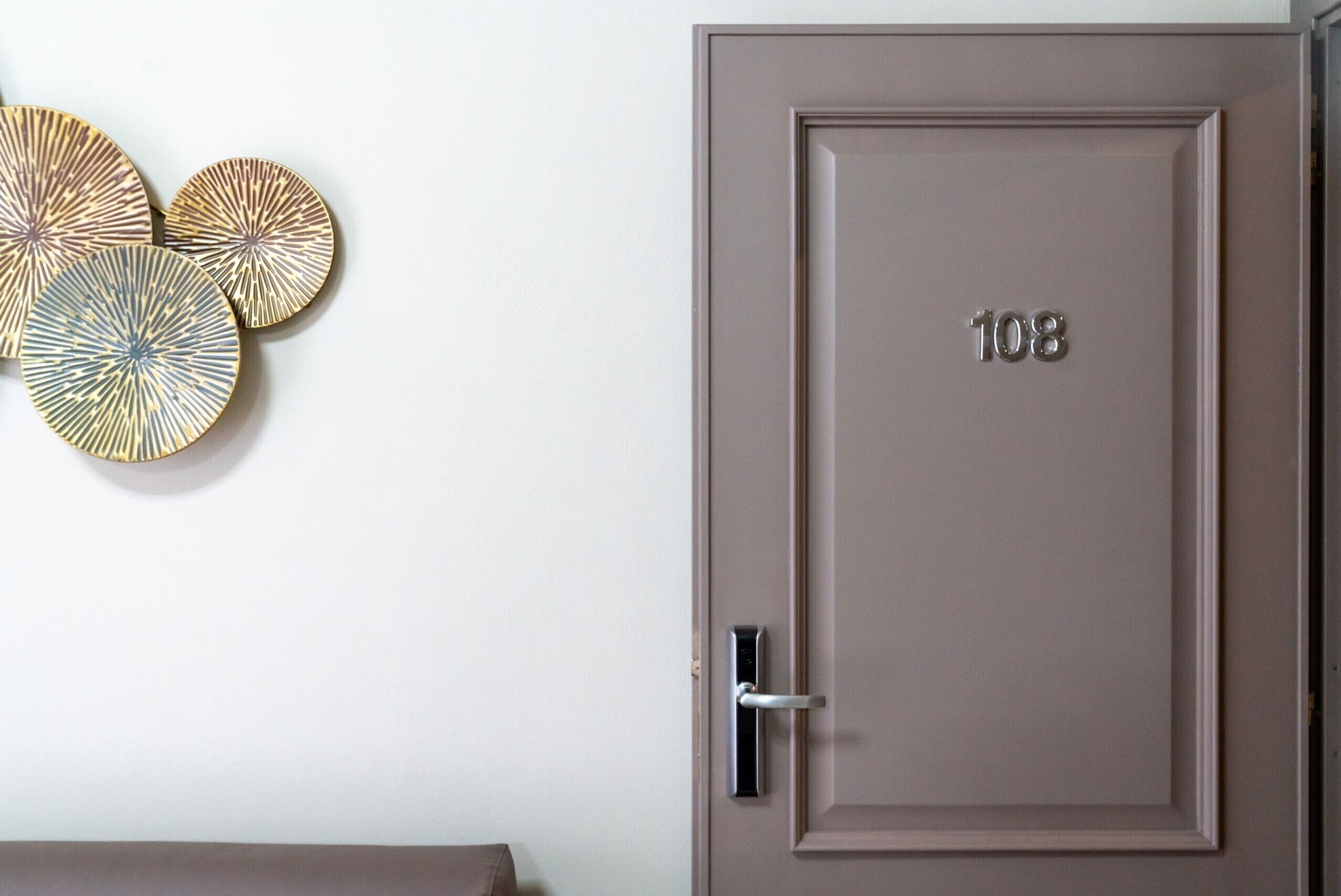 A door with the number 108, a modern handle, and three decorative wall art pieces.