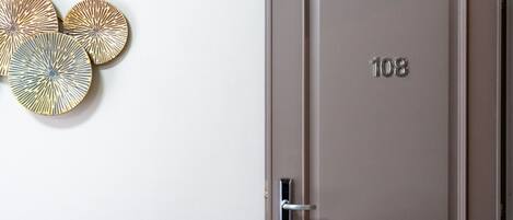 A door with the number 108, a modern handle, and three decorative wall art pieces.