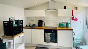 A modern kitchen with white cabinets, a wooden countertop, and a built-in oven. There is a sink with a faucet, a microwave, and a toaster. A red "no smoking" sign is visible on the wall. - Modern Private Guest Suite Near Heathrow Free Parking & Garden (Feltham)