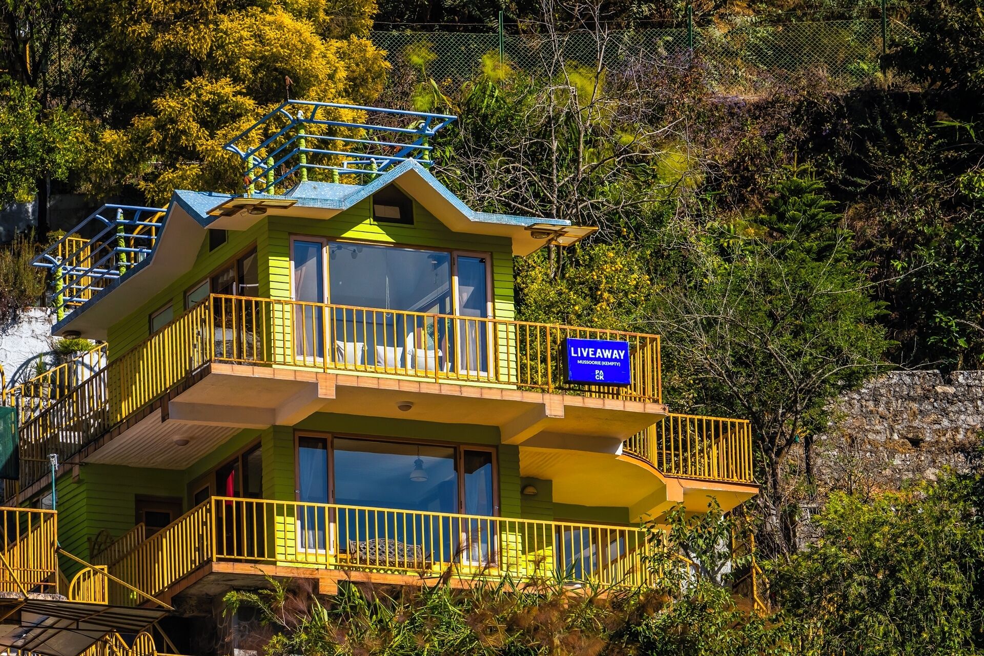 A multi-level building with a 'LiveAway' sign, balconies, and a view of surrounding greenery.