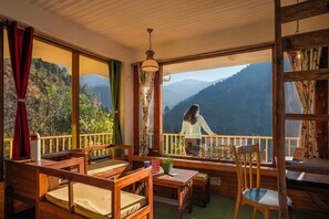 Habitación con balcón y vistas a las montañas, muebles de madera y una lámpara colgante.