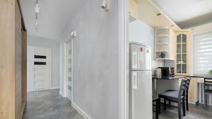 Eine moderne Küche mit Einbaukühlschrank, Essbereich mit Stühlen und einem Fenster mit Jalousien.