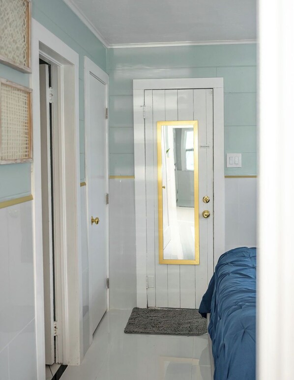 A hallway with a white door, a mirror, and a blue bed. - Modern & Quiet Oasis, 1 minute walk to the Beach (Madeira Beach)