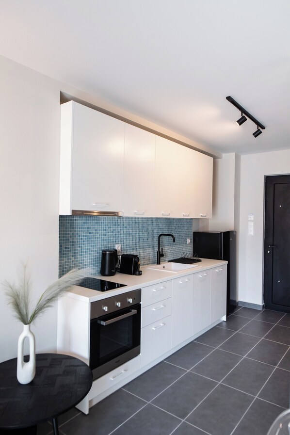 Una cocina moderna con armarios blancos, una estufa negra y un salpicadero de azulejos azules.
