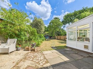A backyard with a patio area, a white shed, and a garden. - Rockford Cottage 3 Bed New Forest House & Garden (Bransgore)