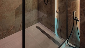 Eine moderne Dusche mit Glastrennwand, Marmorwänden und integrierter Beleuchtung.
