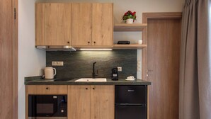 Eine kleine Küche mit Holdekor-Schränken, einer eingebauten Mikrowelle, einer Kaffeemaschine und einem Kühlschrank.