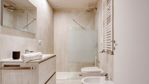 Een moderne badkamer met een douche, wastafel en toilet met spuitfunctie.