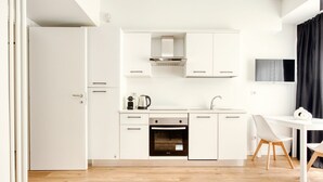 Een moderne keuken met witte kasten, een ingebouwde oven en een koffiezetapparaat.