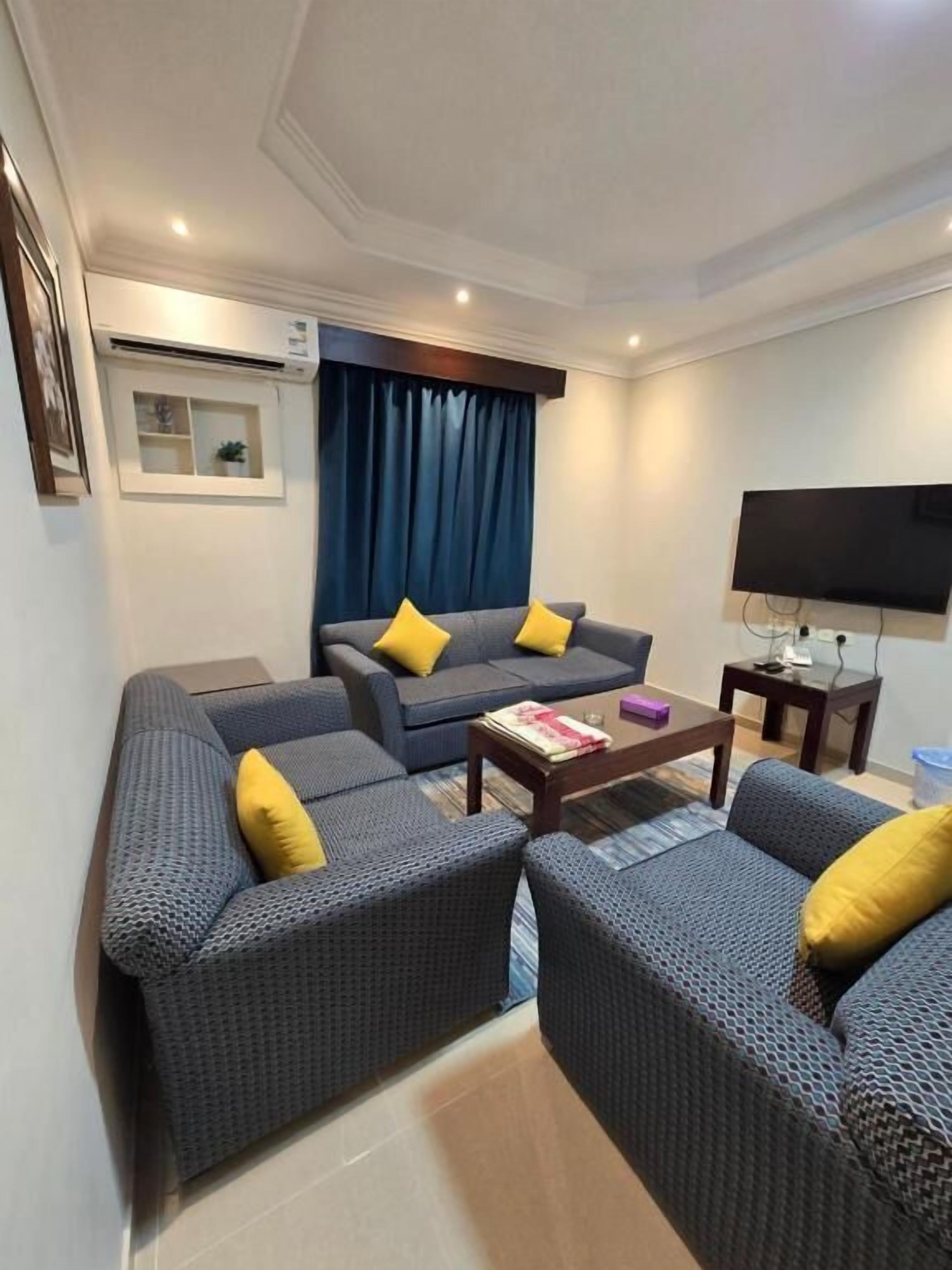 A modern living room with a sofa set, a coffee table, and a flat-screen TV.