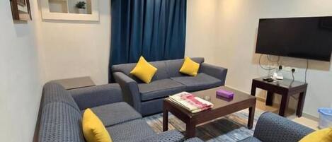 A modern living room with a sofa set, a coffee table, and a flat-screen TV.