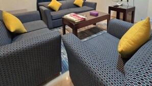 A modern living room with two sofas, a coffee table, a flat-screen TV, and a small side table. - Makarem Najd 5 - Al Aqiq (Riyadh)