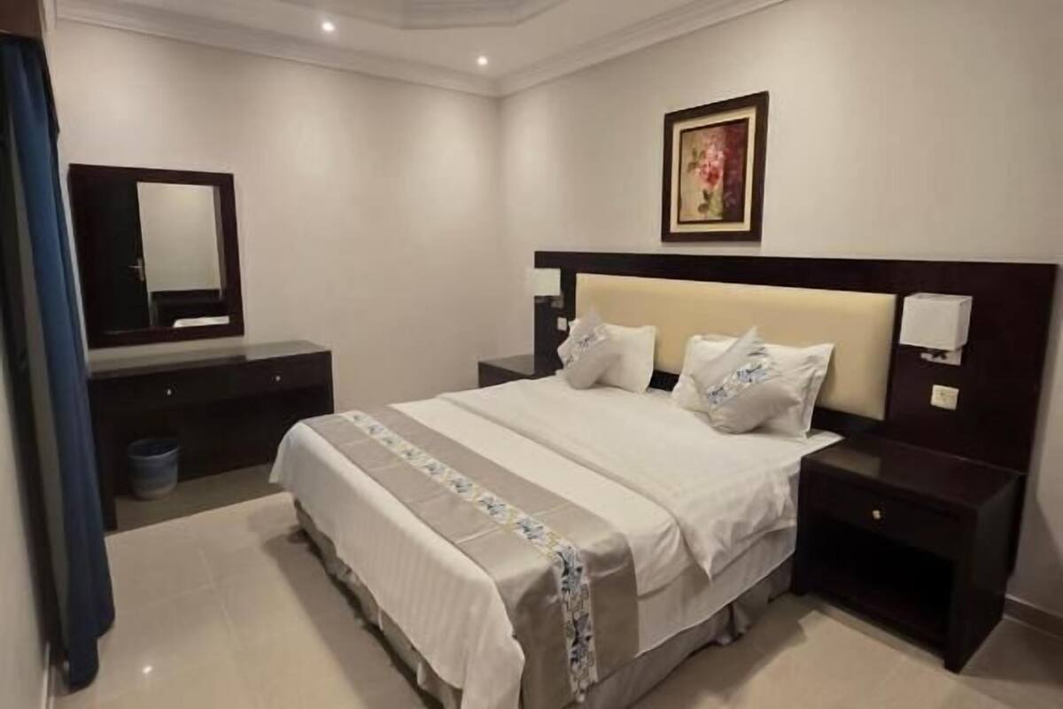Een moderne hotelkamer met een groot bed, nachtkastjes, een spiegel en een ingelijste foto aan de muur.