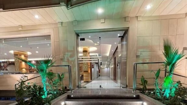 A hotel entrance with a staircase leading to the lobby, flanked by planters with green plants. - Makarem Najd 5 - Al Aqiq (Riyadh)