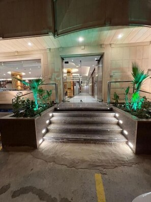 A hotel entrance with a staircase leading to the lobby, flanked by planters with green plants. - Makarem Najd 5 - Al Aqiq (Riyadh)