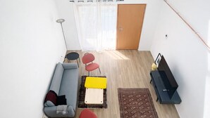 Een moderne woonkamer met een bank, fauteuils, een klein tafeltje, een vloerkleed en een piano.