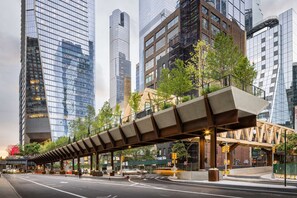 A modern urban street with high-rise buildings, a pedestrian overpass, and a traffic light. - Steps to Times Square | Free Breakfast & Fitness (New York)