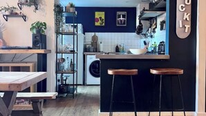 Une cuisine moderne avec un coin bar, un lave-linge et une étagère ornée de plantes.