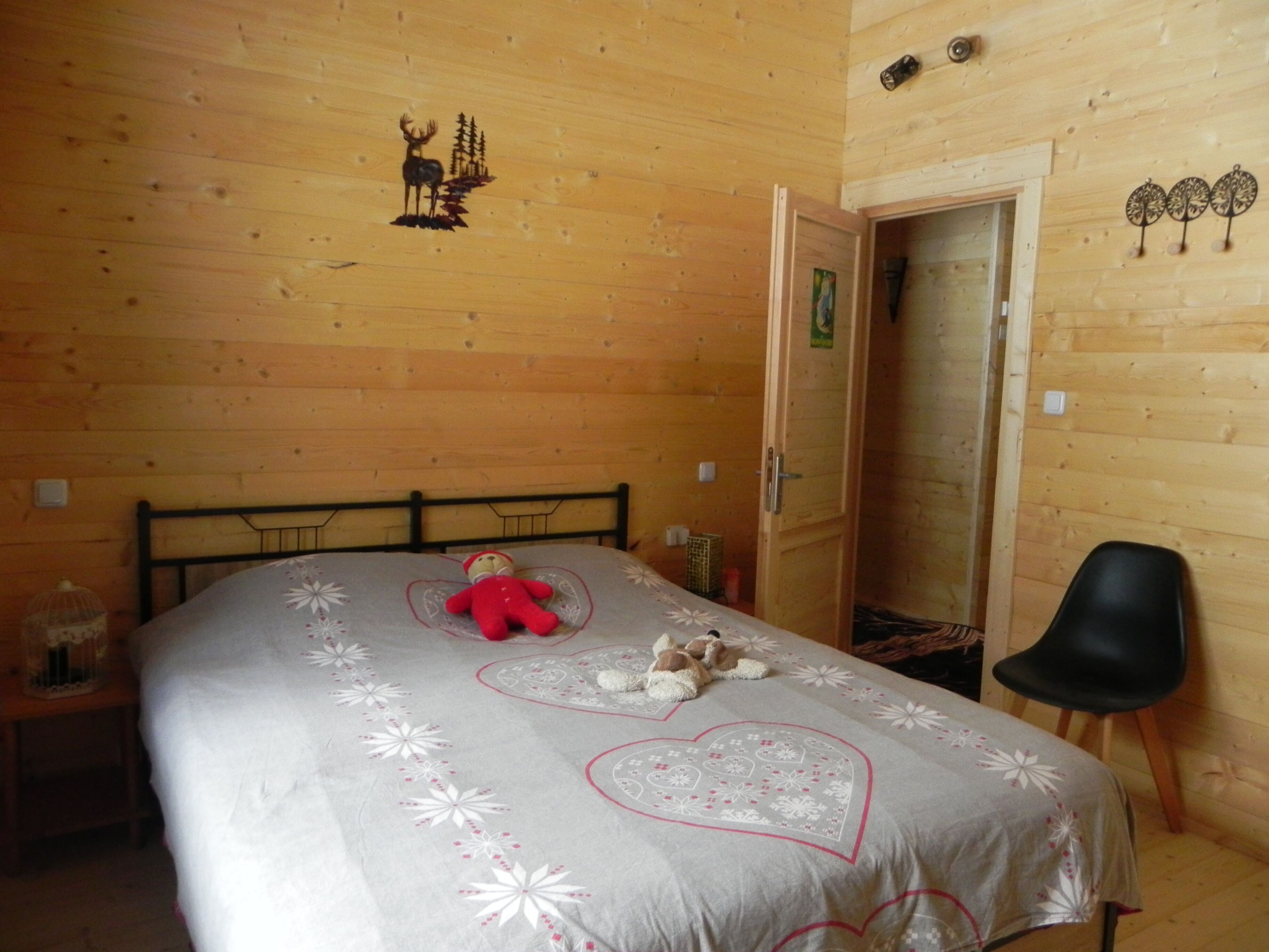 Een houten kamer met een bed, een stoel en een deur.