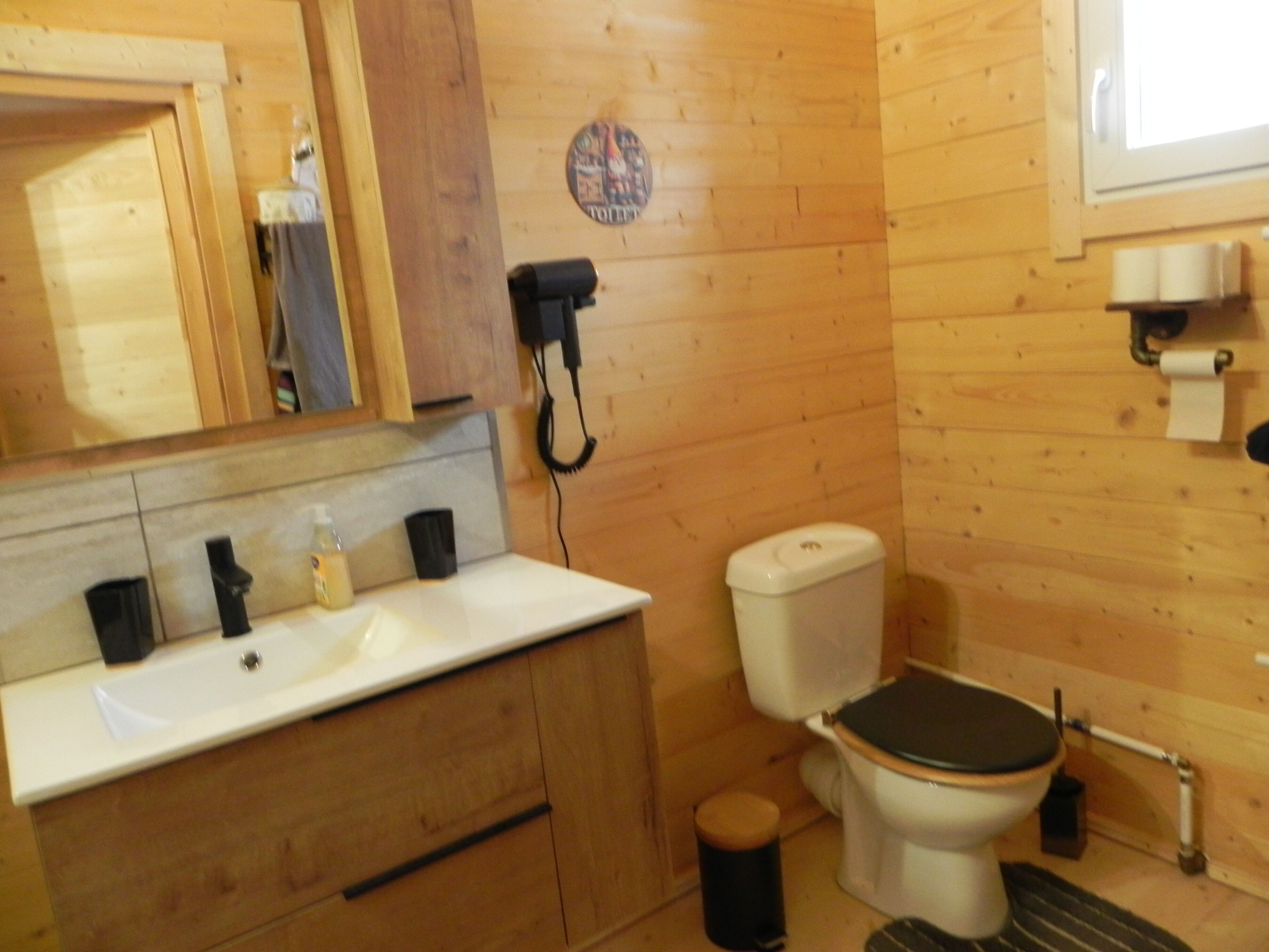 Un baño con paneles de madera, un lavamanos, un inodoro y un espejo.