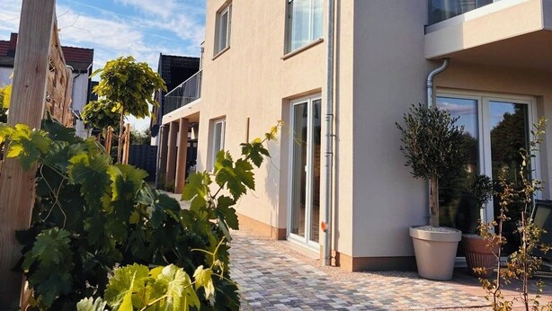 A modern two-story building with a flat roof, large windows, and a balcony with glass railings. - Vacation home Lounis - Apartment 1 (Bützow)