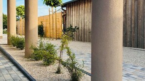 A courtyard with a pergola structure, gravel pathways, and small plants. - Vacation home Lounis - Apartment 1 (Bützow)